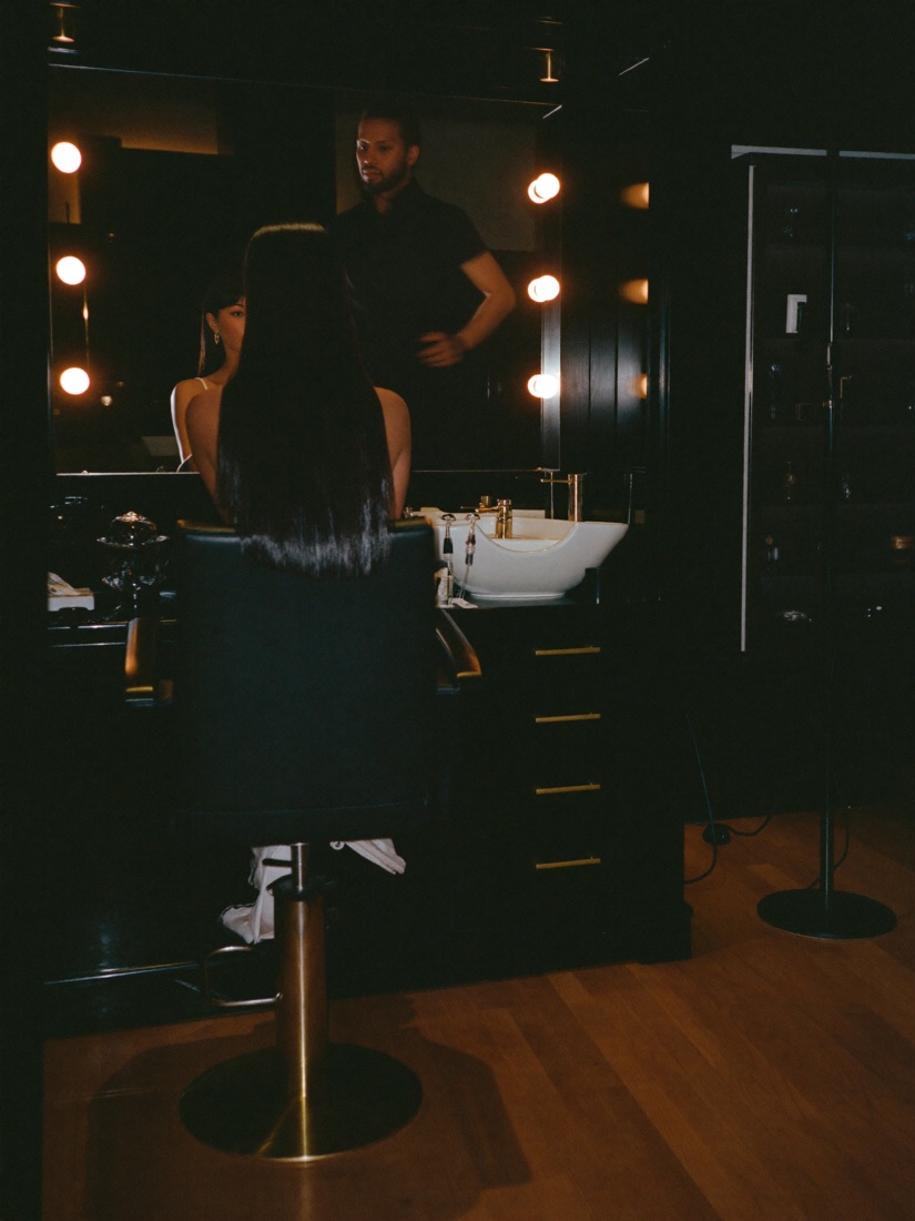 A stylist stepping back from a client with freshly finished glossy hair at a mirrored station.